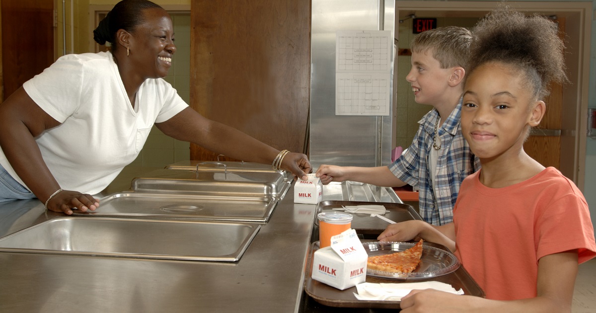 Children receive lunch from school cafeteria attendant