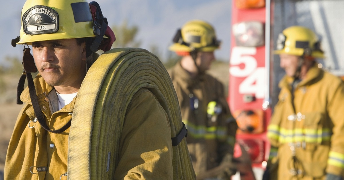 Fireman in full gear carries fire hose