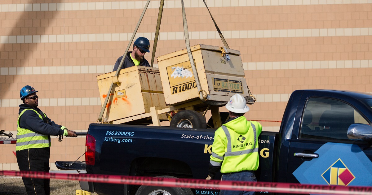 Workers use equipment to lift heavy boxes into truck